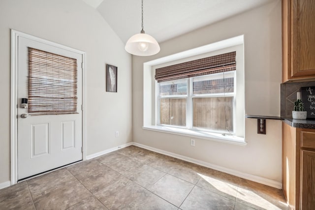unfurnished dining area with vaulted ceiling, baseboards, and light tile patterned floors