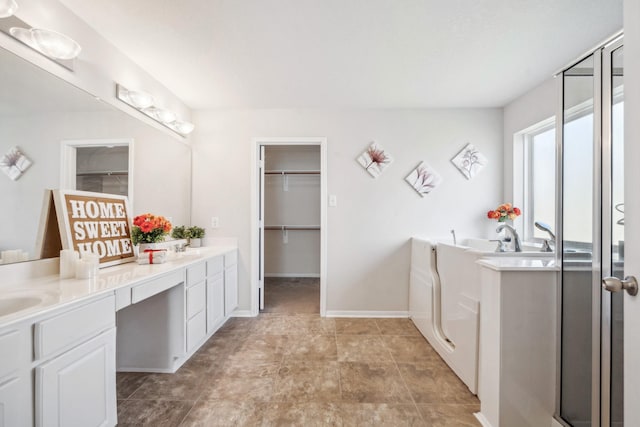 bathroom featuring a walk in closet, a garden tub, a sink, and double vanity