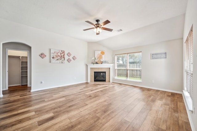 unfurnished living room featuring vaulted ceiling, light wood-type flooring, baseboards, a fireplace, and ceiling fan
