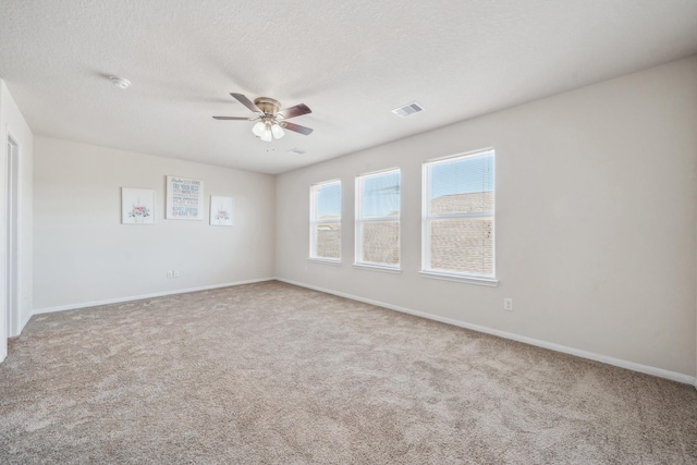 empty room featuring carpet floors, visible vents, baseboards, and ceiling fan