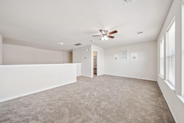 unfurnished room with carpet floors, visible vents, baseboards, and ceiling fan