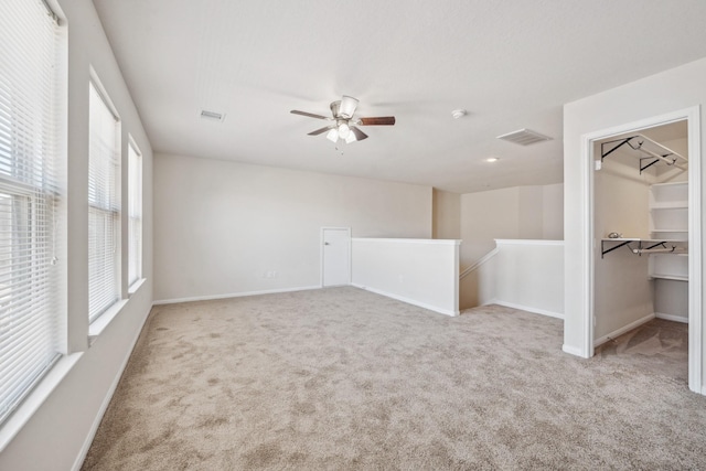carpeted empty room featuring ceiling fan, baseboards, and visible vents