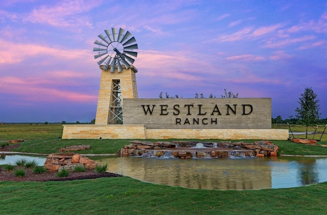 community sign with a yard and a water view