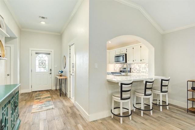 29 Clara Barton Ln, Galveston, TX 77551 - entryway featuring visible vents, crown molding, arched walkways, baseboards, and light wood-style floors