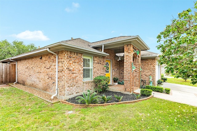 29 Clara Barton Ln, Galveston, TX 77551 - view of front facade featuring brick siding, roof with shingles, fence, and a front yard