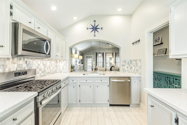 29 Clara Barton Ln, Galveston, TX 77551 - kitchen featuring backsplash, appliances with stainless steel finishes, vaulted ceiling, a sink, and white cabinets