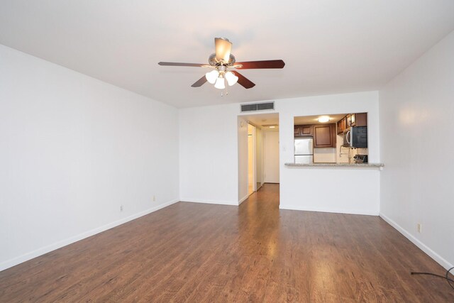 unfurnished living room featuring dark wood-style flooring, visible vents, baseboards, and ceiling fan