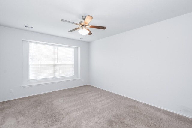 unfurnished room with carpet floors, visible vents, baseboards, and ceiling fan