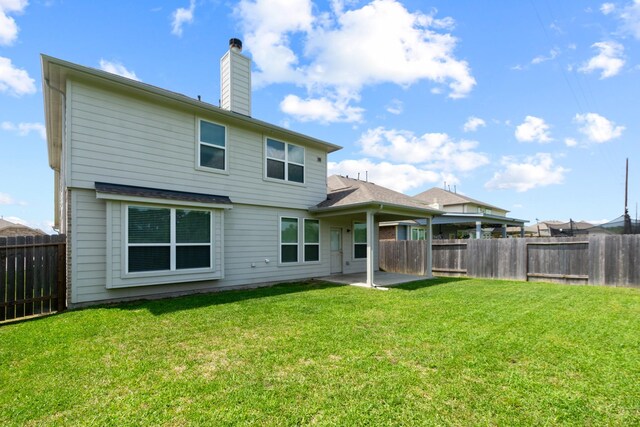 rear view of house featuring a patio area, a lawn, a chimney, and a fenced backyard