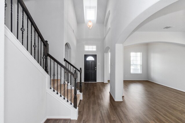 foyer featuring arched walkways, a healthy amount of sunlight, wood finished floors, and visible vents