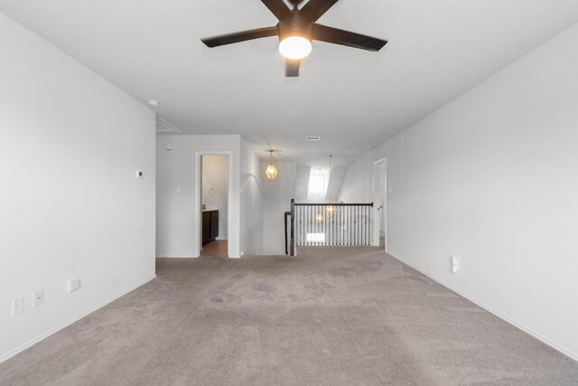 unfurnished living room with attic access, a ceiling fan, and carpet
