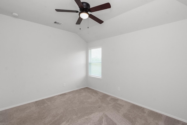 empty room with lofted ceiling, visible vents, a ceiling fan, carpet floors, and baseboards