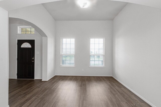 foyer featuring baseboards, dark wood-style floors, and arched walkways