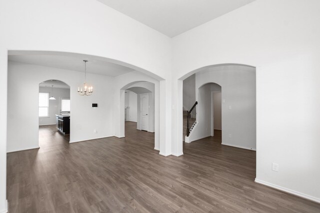 interior space featuring baseboards, stairs, dark wood-style floors, and an inviting chandelier