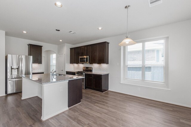 kitchen featuring a sink, decorative backsplash, arched walkways, stainless steel appliances, and visible vents