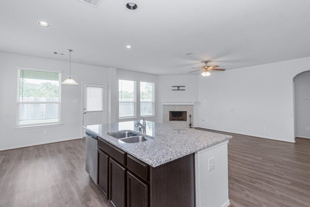 kitchen featuring a ceiling fan, dark brown cabinets, wood finished floors, open floor plan, and a tile fireplace