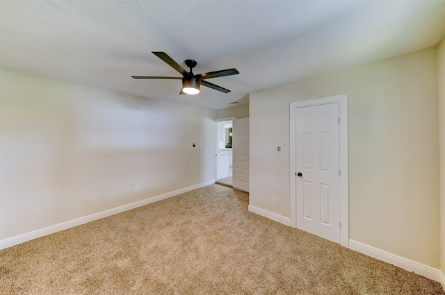 carpeted spare room featuring baseboards and ceiling fan