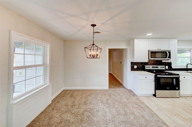 kitchen featuring stainless steel appliances, tasteful backsplash, a chandelier, white cabinetry, and decorative light fixtures