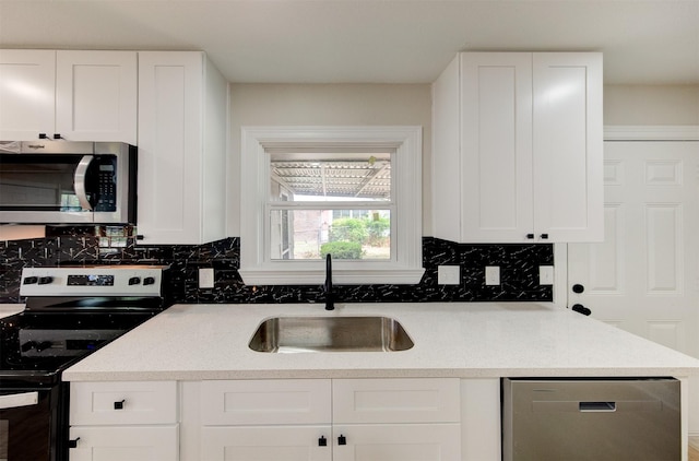 kitchen featuring tasteful backsplash, a sink, appliances with stainless steel finishes, and white cabinetry