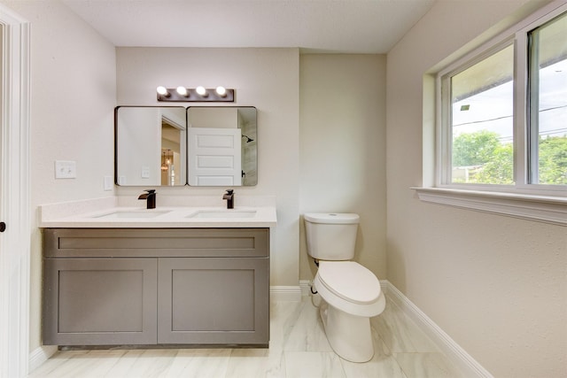 full bathroom featuring baseboards, toilet, double vanity, and a sink