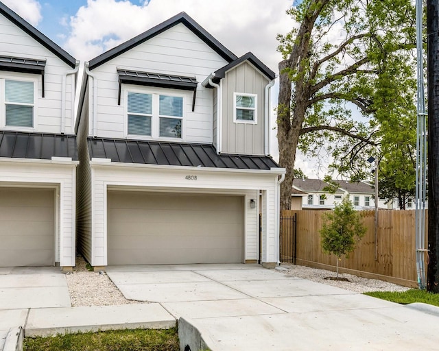 view of front of home with a standing seam roof, driveway, metal roof, fence, and a garage