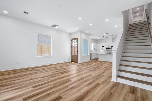 unfurnished living room with light wood finished floors, stairs, visible vents, and recessed lighting