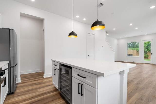 kitchen with light wood-style flooring, freestanding refrigerator, recessed lighting, decorative light fixtures, and beverage cooler
