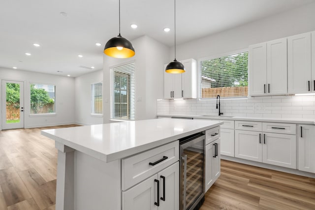 kitchen with light countertops, light wood-style flooring, a sink, and beverage cooler