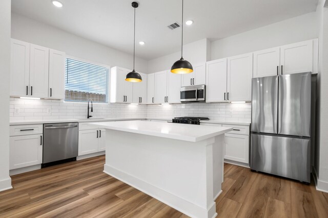 kitchen with a sink, decorative backsplash, white cabinets, appliances with stainless steel finishes, and visible vents