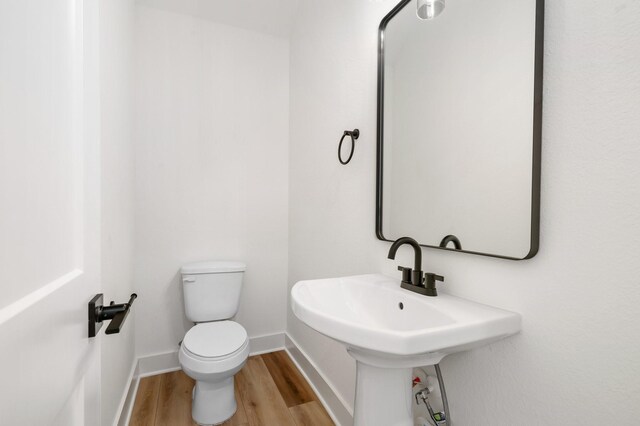 bathroom with baseboards, toilet, and wood finished floors