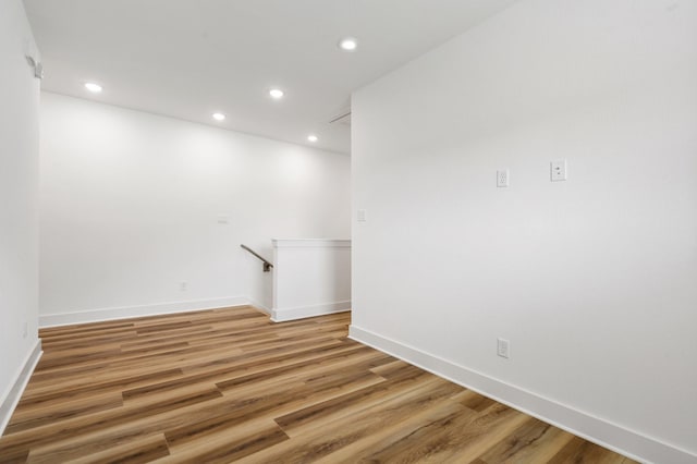 empty room with recessed lighting, light wood-type flooring, and baseboards