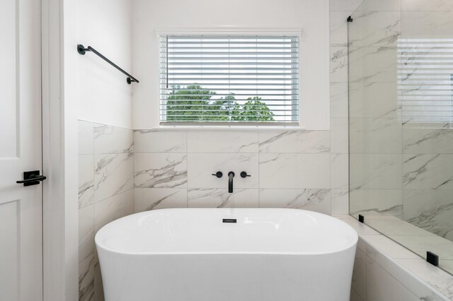 full bathroom featuring tile walls and a soaking tub