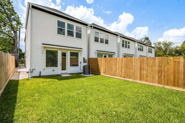 rear view of property featuring a yard, a fenced backyard, and central AC unit