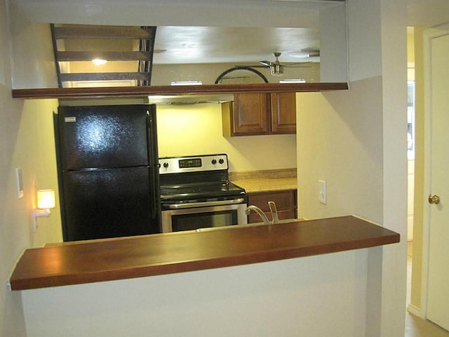 kitchen with stainless steel range with electric cooktop, freestanding refrigerator, and extractor fan