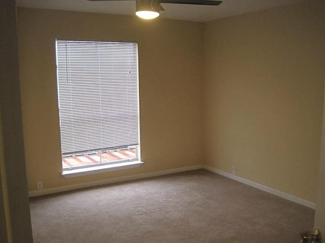 spare room featuring carpet, a ceiling fan, and baseboards