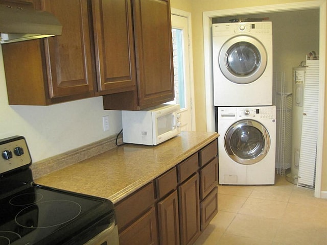 laundry room with light tile patterned flooring, stacked washer and dryer, and laundry area