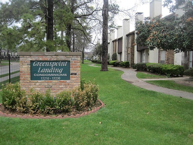 community / neighborhood sign featuring fence and a yard