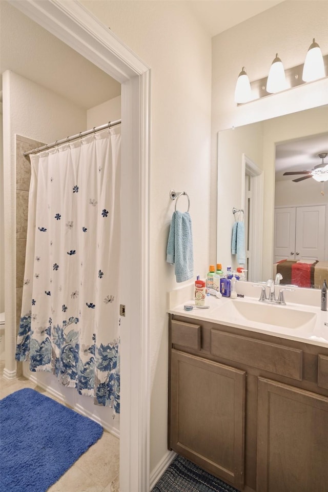 ensuite bathroom with ceiling fan, vanity, shower / bathtub combination with curtain, and tile patterned floors