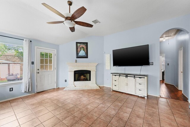 unfurnished living room featuring ceiling fan, tile patterned flooring, lofted ceiling, a high end fireplace, and visible vents