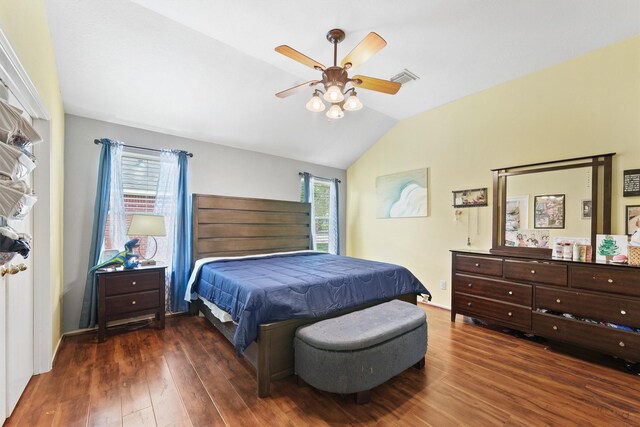 bedroom with a ceiling fan, vaulted ceiling, wood finished floors, and visible vents