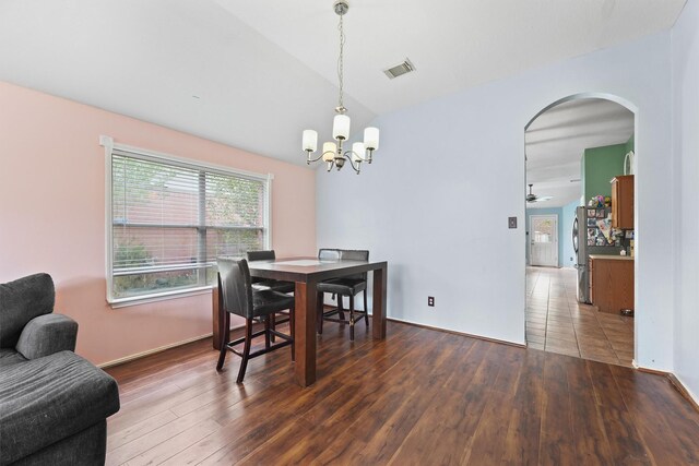 dining room with arched walkways, vaulted ceiling, visible vents, and hardwood / wood-style flooring