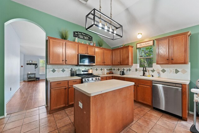 kitchen with a sink, appliances with stainless steel finishes, lofted ceiling, and a healthy amount of sunlight