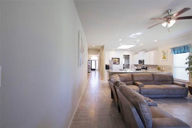 2757 Maxway Ct, League City, TX 77573 - living room with baseboards, a skylight, ceiling fan, and stone tile floors