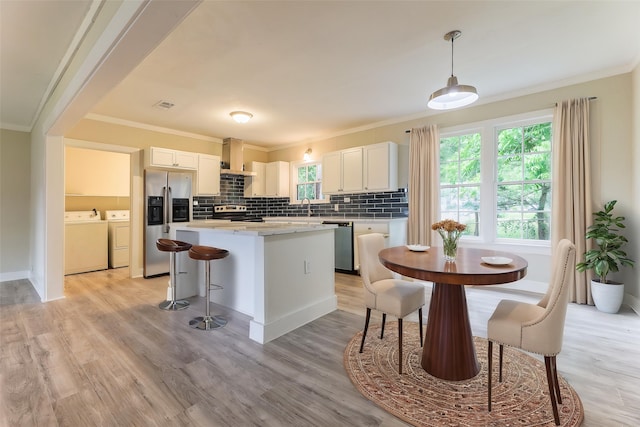 208 W Jefferson St, Trinity, TX 75862 - kitchen featuring appliances with stainless steel finishes, washing machine and clothes dryer, a center island, ornamental molding, and decorative backsplash