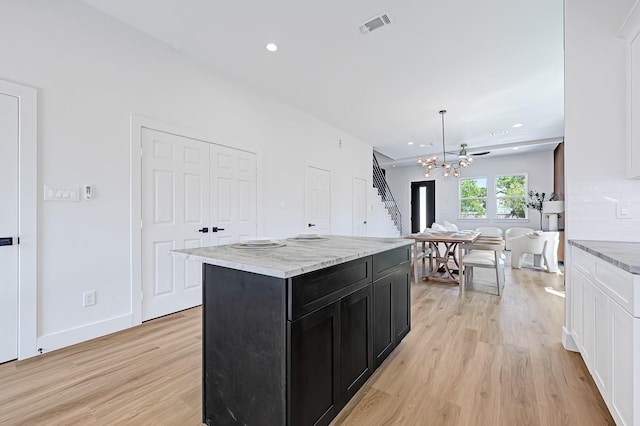 6726 Dumble St, Houston, TX 77021 - kitchen with dark cabinetry, a chandelier, light wood-type flooring, light stone counters, and a center island