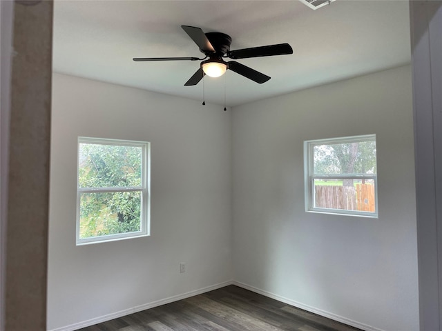 spare room with dark wood finished floors, baseboards, a ceiling fan, and plenty of natural light