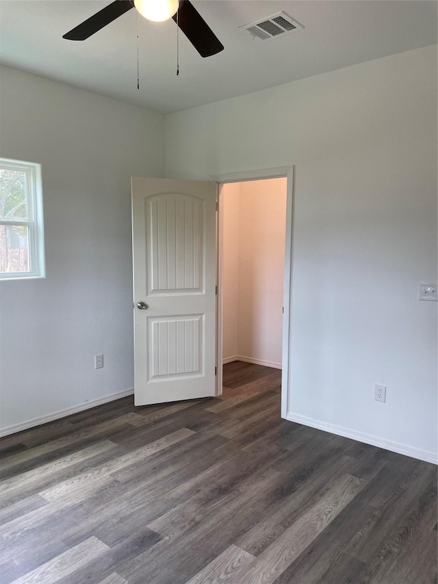 spare room with baseboards, visible vents, dark wood-type flooring, and ceiling fan