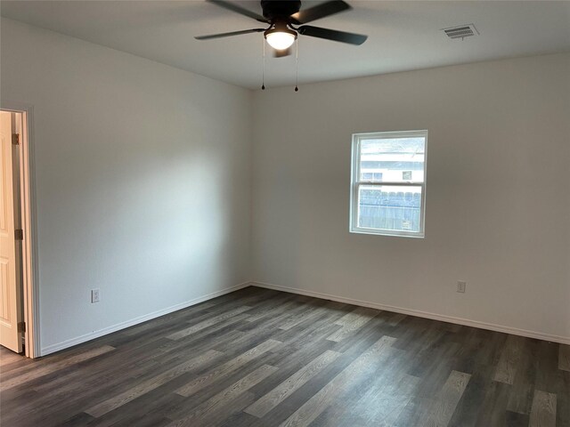 empty room featuring dark wood-type flooring, visible vents, baseboards, and ceiling fan