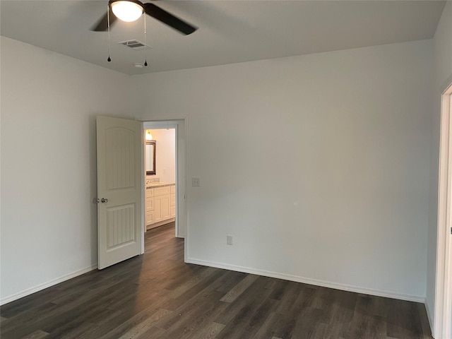 spare room featuring baseboards, visible vents, a ceiling fan, and dark wood-style floors
