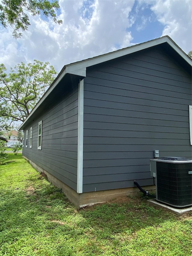 view of side of property with a lawn and central air condition unit